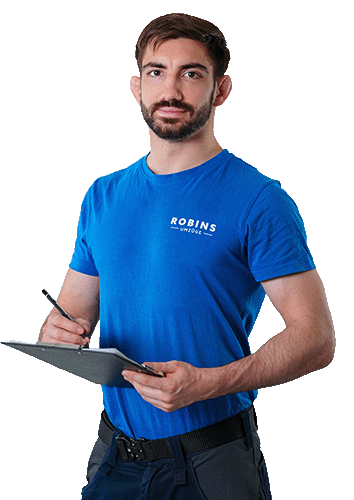 Ein Mann mit Bart und einem blauen „ROBINS“-T-Shirt hält ein Klemmbrett und einen Stift.