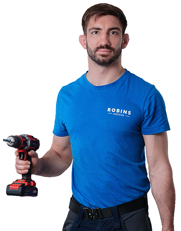 Ein Mann in einem blauen T-Shirt hält eine rot-schwarze Bohrmaschine.